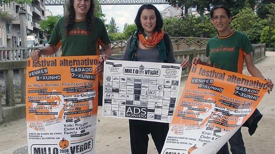 Tres organizadores del festival alternativo &quot;Millo Verde&quot;muestran los carteles.