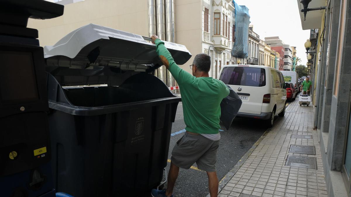 Un vecino tira la basura en un contenedor de la calle Buenos Aires.