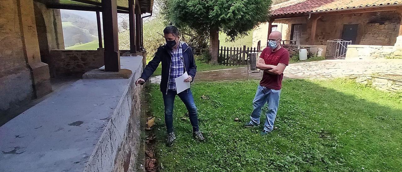 Rafael Palacios observa la obra realizada en el muro del templo, con el escrito presentado en la Junta en mano y con Manuel Alberto Vicente, portavoz local de Podemos, a su lado. | D. M.