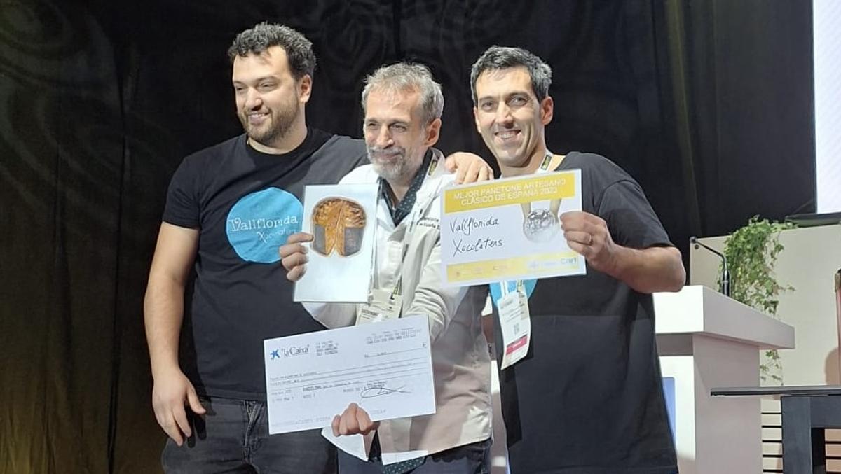 Lluís Costa (izquierda) y su hermano Gerard flanquean a Daniel Jordà, miembro del jurado que ha considerado que los 'panettones' de Vallflorida Xocolaters son los mejores 'panettones' de España de 2023.