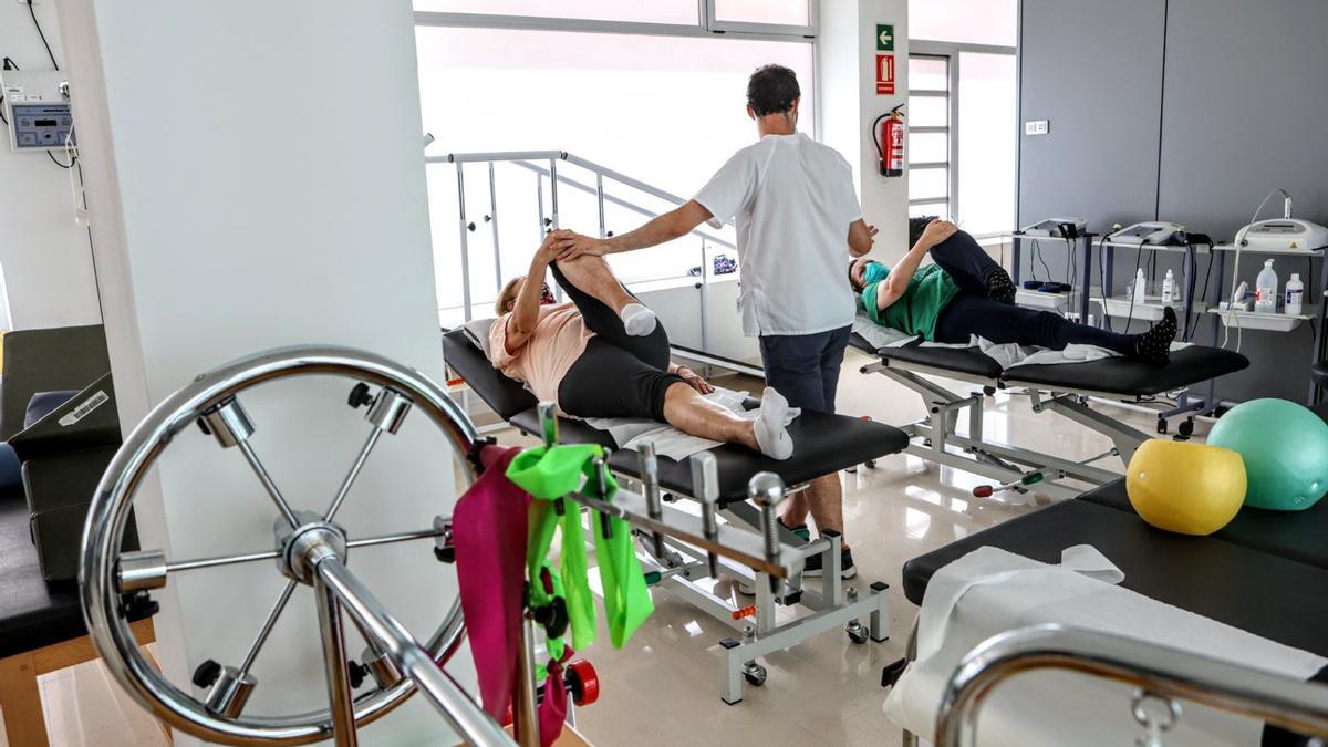 Un fisioterapeuta atiende a dos personas en un centro de salud de Alicante.