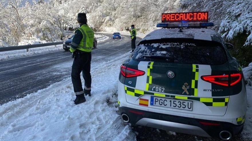 Una patrulla de la Guardia Civil controla el tráfico en una carretera nevada