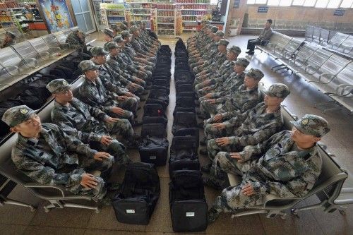 New recruits of China's People Liberation Army soldiers sit at waiting area of a railway station in Taiyuan