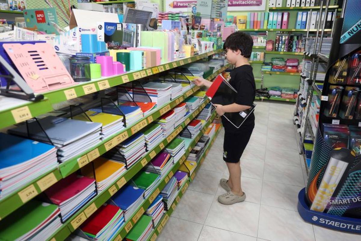 Un niño revisa unos cuadernos en una papalería de Vilagarcía.