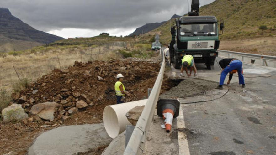 Un grupo de operarios repara un socavón en una carretera de Artenara. | andrés cruz