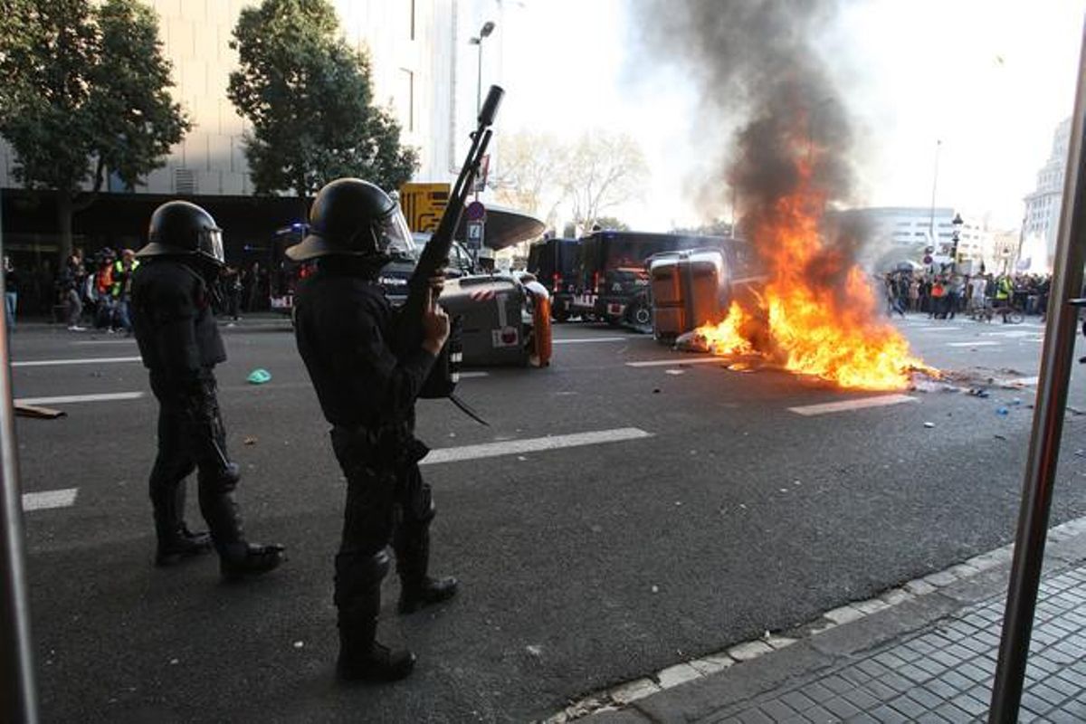 Policías ante unos contenedores incendiados.