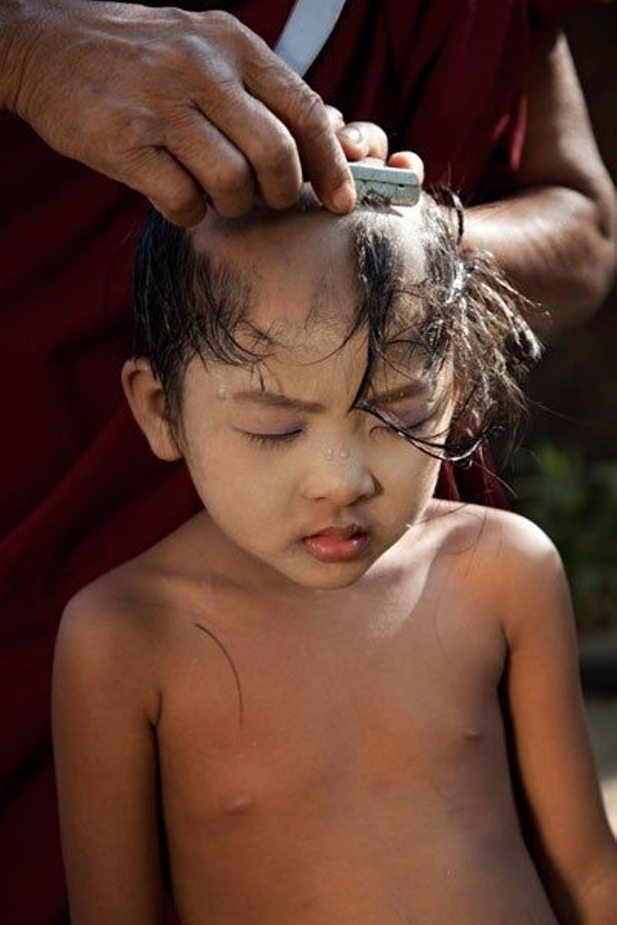Jóven monje budista afeitándose la cabeza en Myanmar.