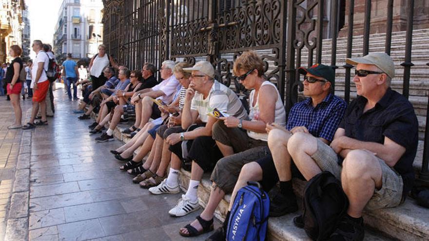 Un grupo de turistas descansa junto a la entrada de la Catedral de Málaga.