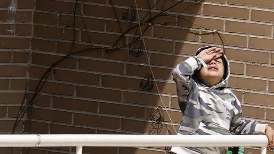 Un niño aburrido en el balcón de su casa, en Madrid.