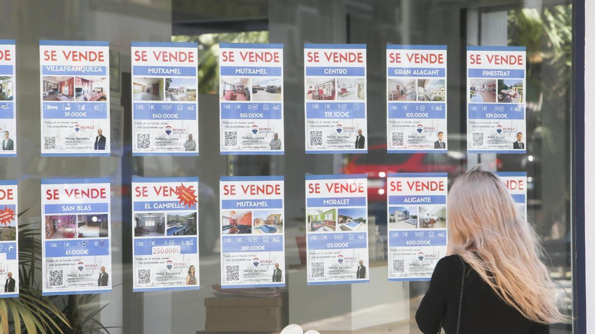 Una mujer mira el escaparate de una inmobiliaria en Alicante.