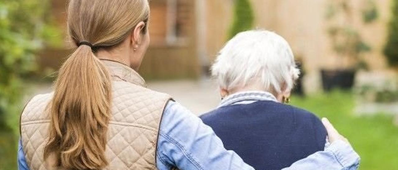 Una mujer dependiente camina junto a una familiar en una visita a una residencia.