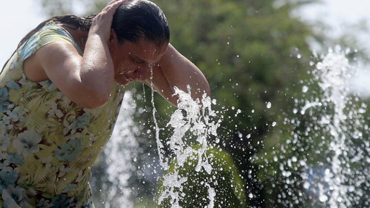 Una mujer se refresca en una fuente.