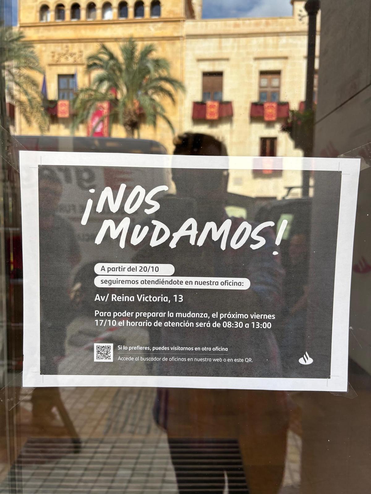 Cartel de aviso a clientes sobre el cierre de la oficina del Banco Santander en la Plaça de Baix de Elche y su nueva ubicación