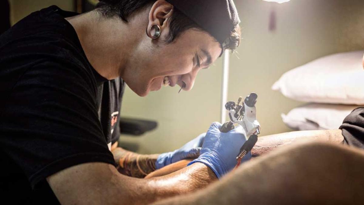 Un alumno tatúa a una persona, en una de las prácticas del curso de tatuaje de Ara Educació