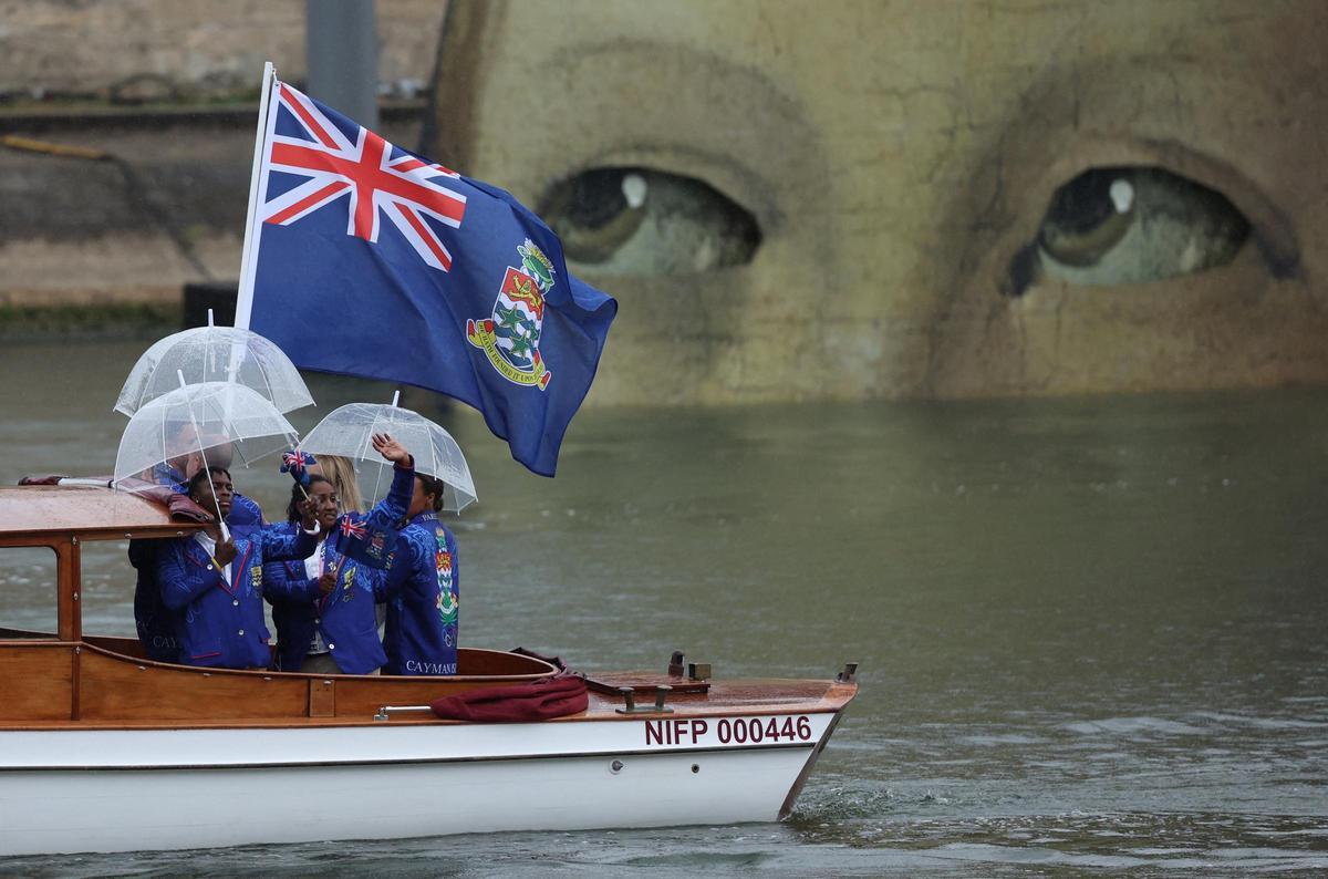 Atletas de las Islas Caimán a bordo de un barco en el desfile flotante en el río Sena durante la ceremonia de apertura.