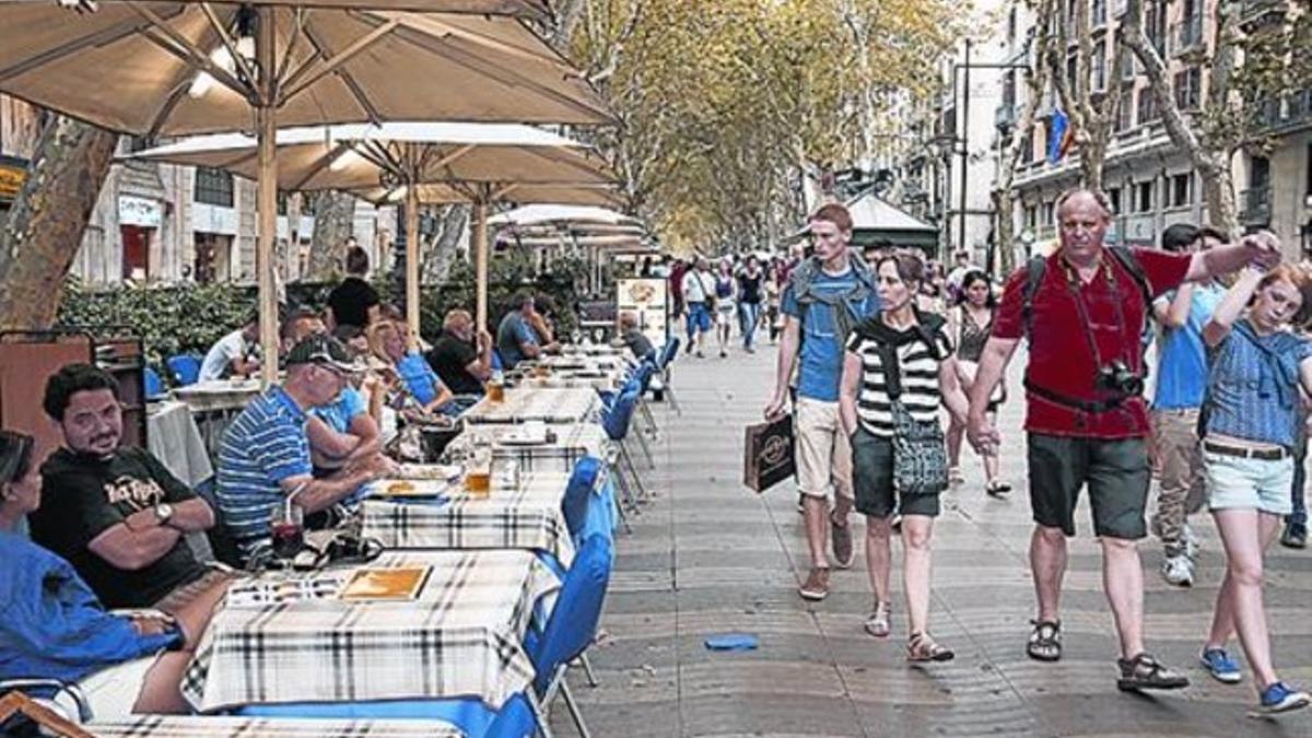 Un grupo de turistas pasa por delante de  una terraza que sirve comidas.