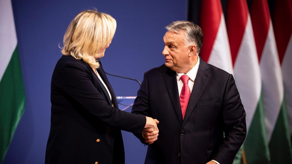 Marine Le Pen y Viktor Orbán se estrechan la mano.