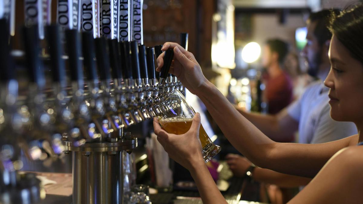 Una camarera llenando un vaso de cerveza.