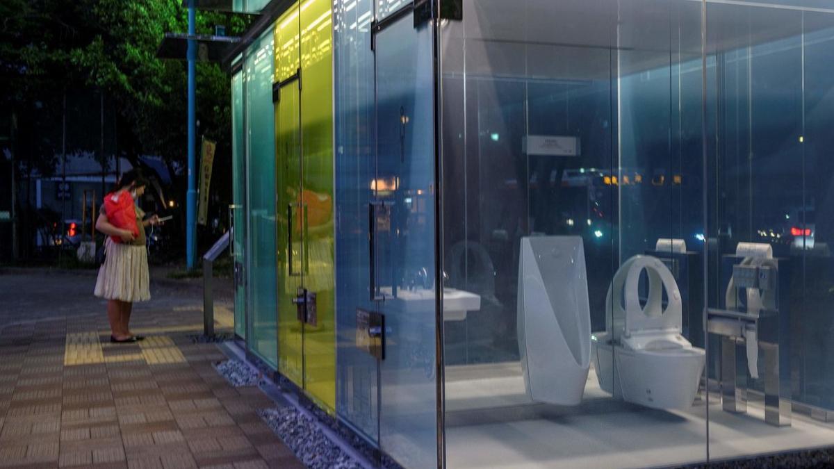 Una mujer observa, curiosa, los nuevos baños transparentes instalados en un parque de Tokio.