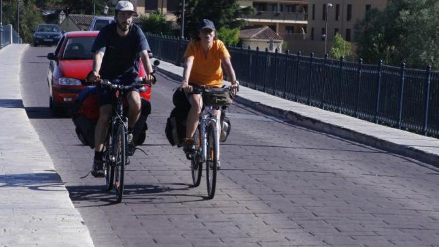 Una pareja de ciclistas circula por el Puente de Piedra de la capital