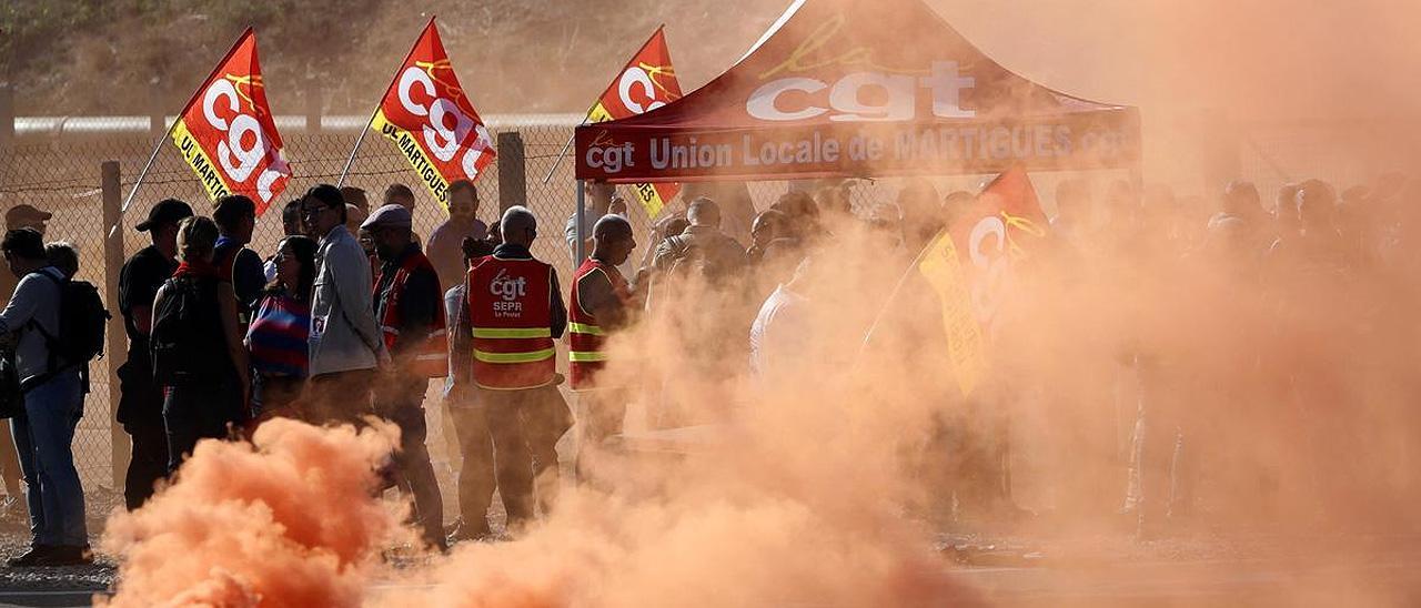 Trabajadores de Total Energies y Esso ExxonMobil lanzan una bomba de humo de colores durante una protesta.