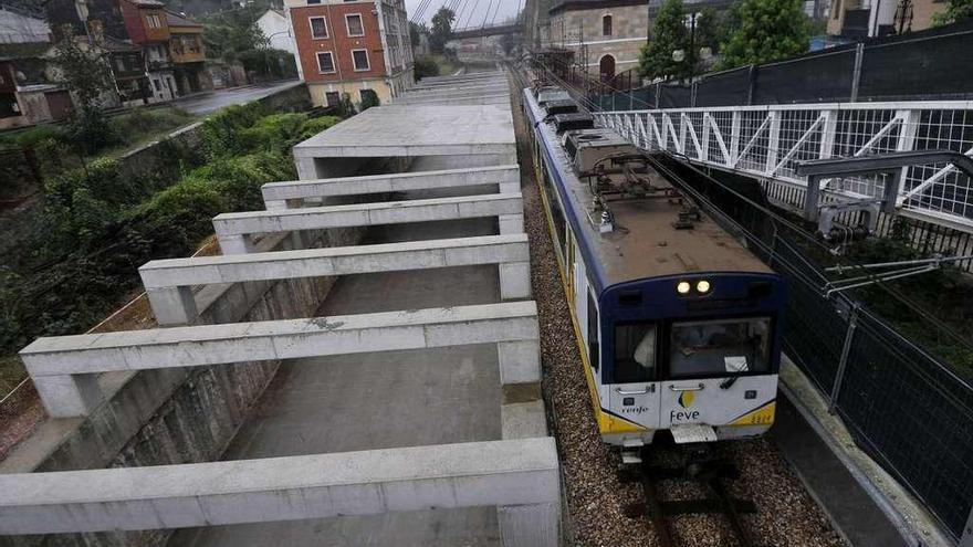 Un tren circula por las vías situadas al lado del inicio del nuevo túnel del soterramiento de Langreo.