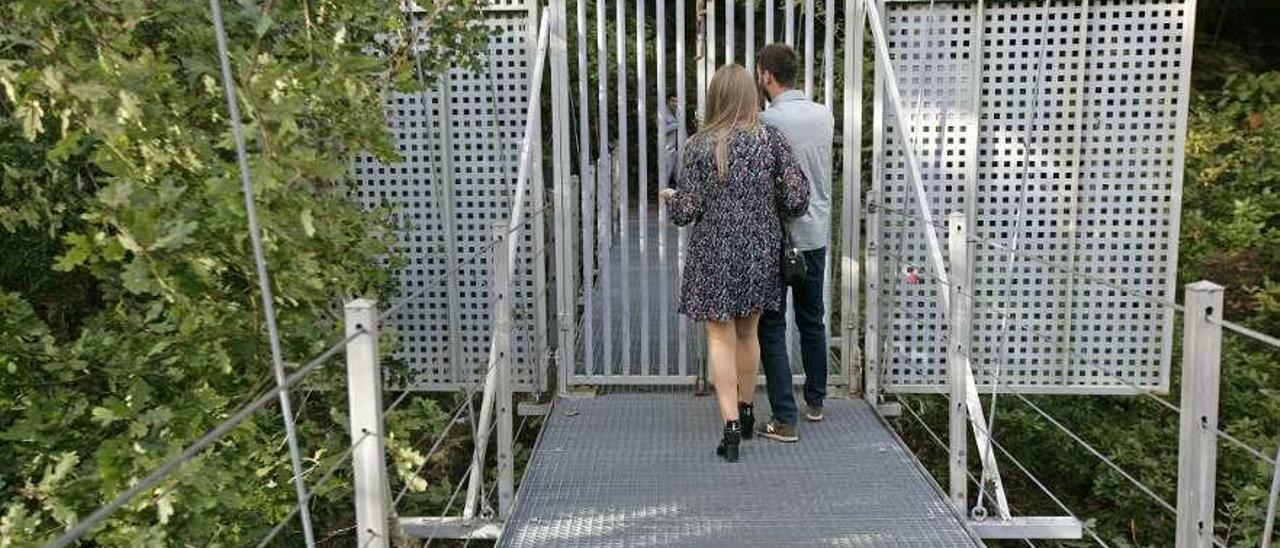 Visitantes, ayer, en el puente colgante ante la puerta cerrada tras cruzar la estructura. // Bernabé/Cris M.V.