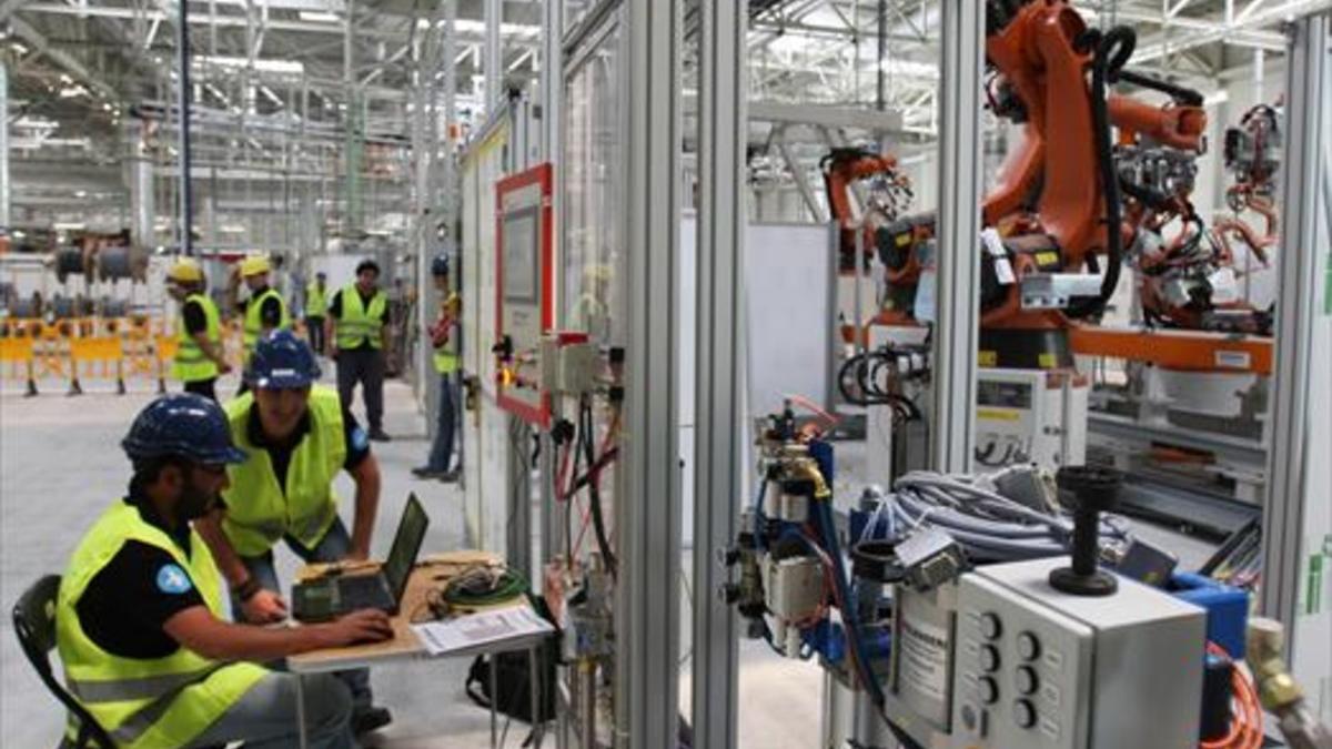 Operarios de la fábrica de Seat en Martorell, trabajando con brazos robotizados.