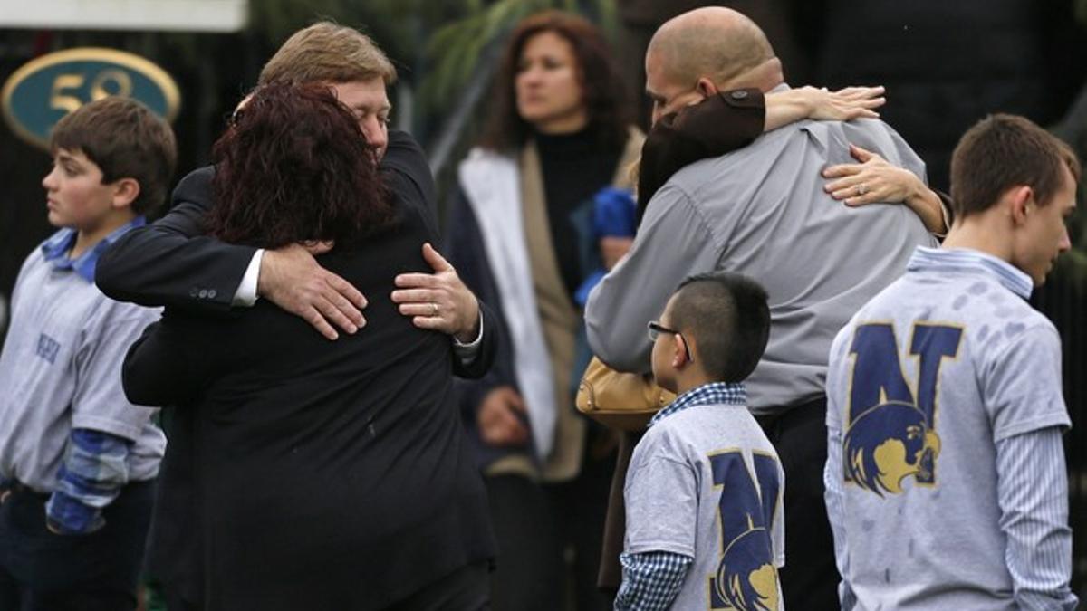 Varias familias se abrazan junto a niños que visten camisetas de Newtown.