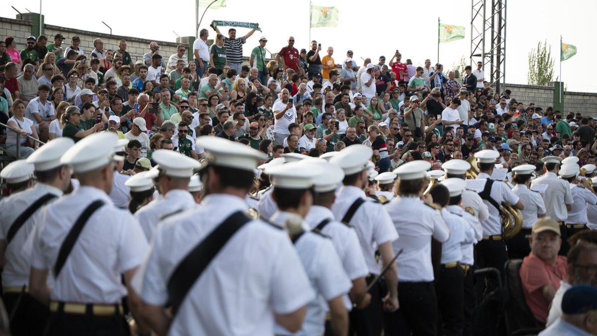 Aficionados ven el paso de la banda del Cristo del Humilladero antes del partido del ascenso ante el Estepona.