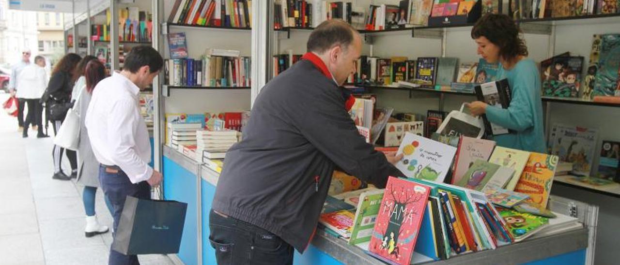 Clientes ojean libros en una de las casetas de la Feira do Libro, en la calle Paseo. |   // IÑAKI OSORIO