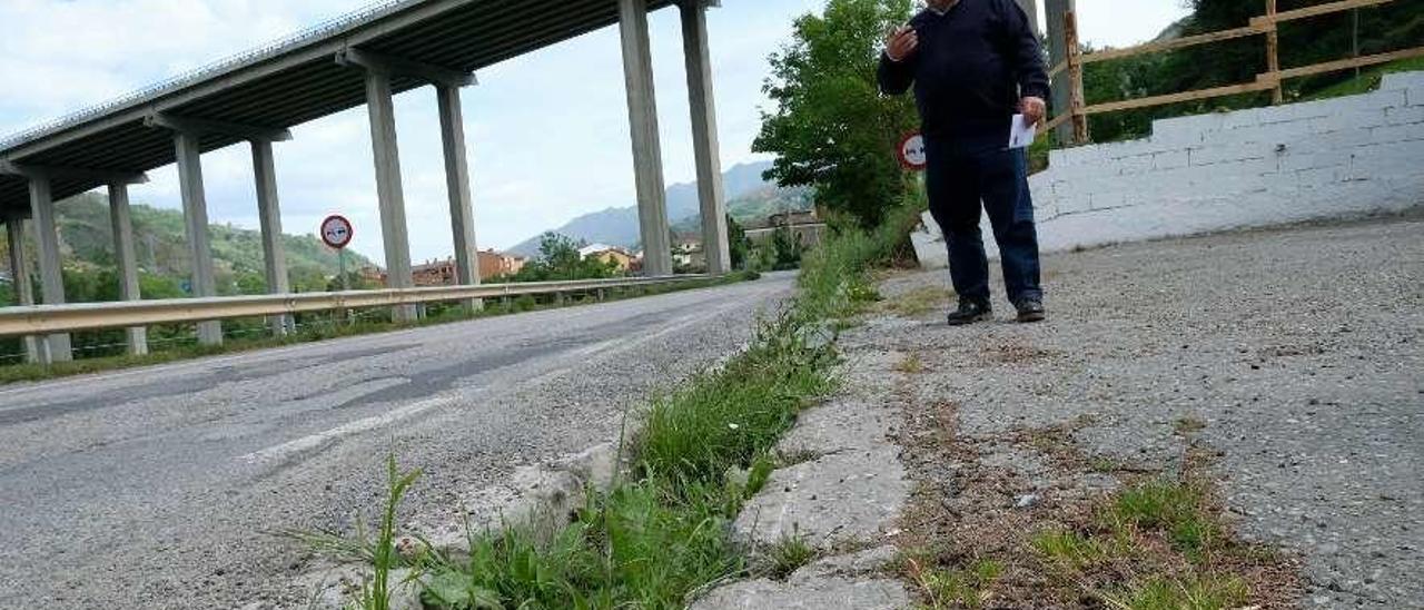 Antonio López muestra el bache en la orilla de la carretera de acceso al cementerio de Campomanes.