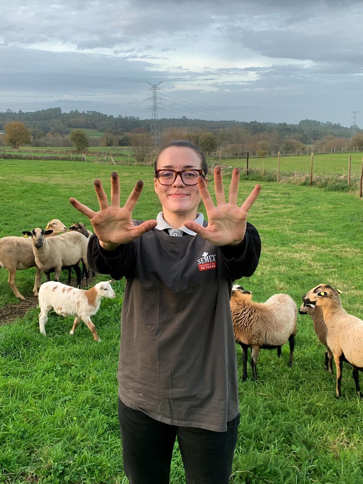 Lucía, con las manos manchadas tras acariciar a Almodóvar, que aparece al fondo a la izquierda junto al resto de las ovejas.