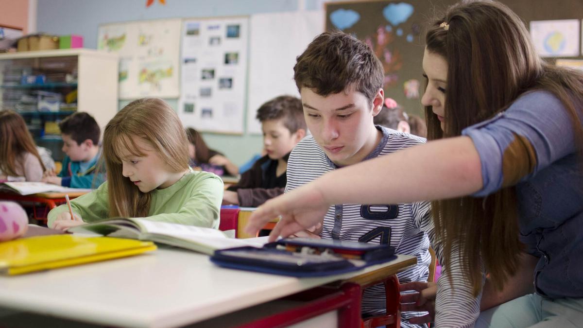Una profesora atiende a un alumno durante una clase.