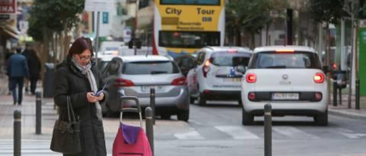 Una mujer con su móvil en la mano en la avenida de los Almendros de Benidorm.