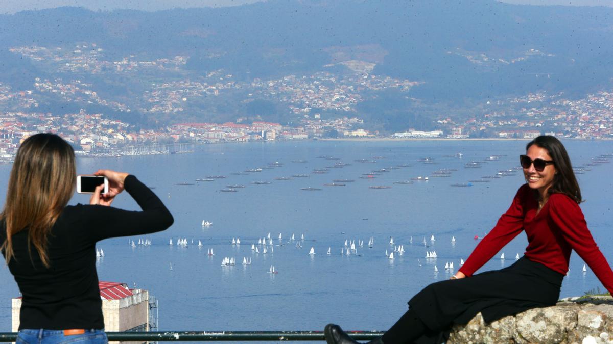 Dos vecinas se hacen una foto desde O Castro con la regata al fondo