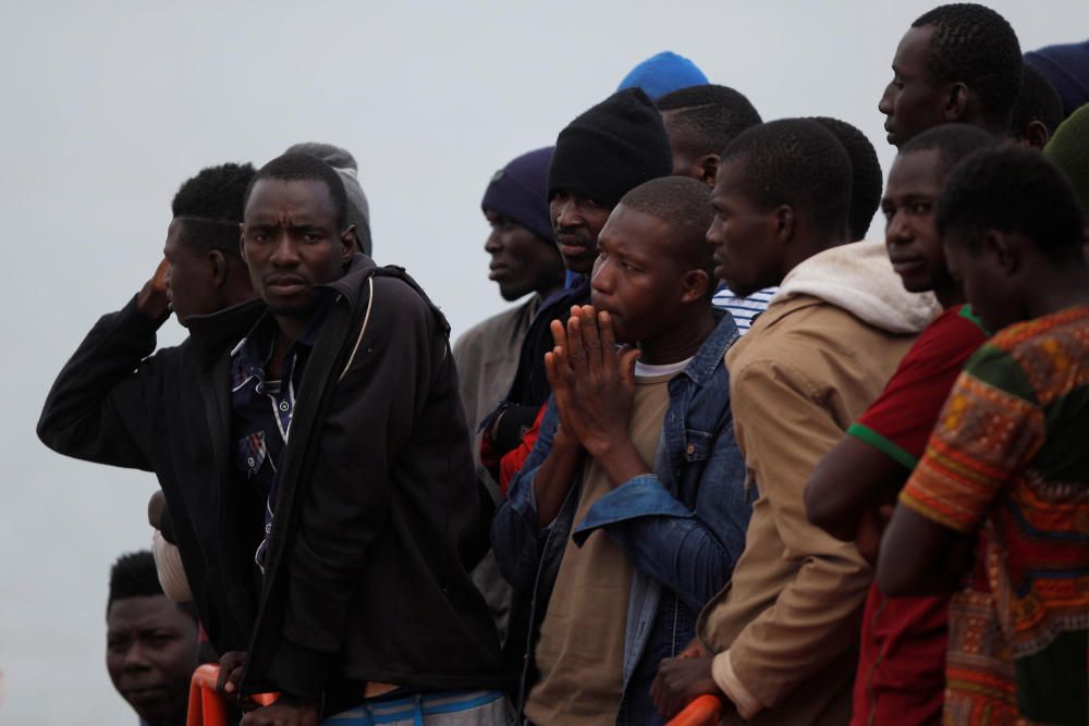 Migrants stand on a rescue boat upon arriving at ...