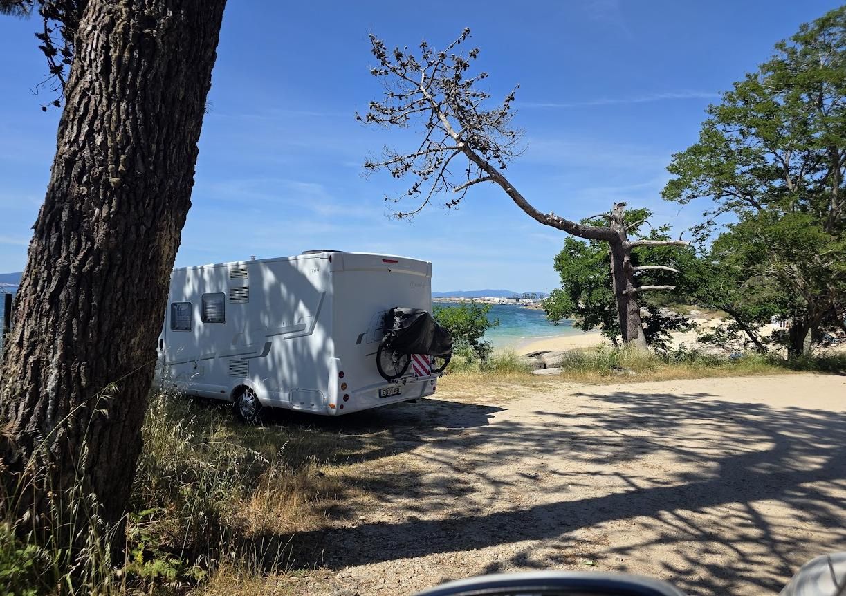 Una autocaravana en la playa de As Pipas, al fondo.