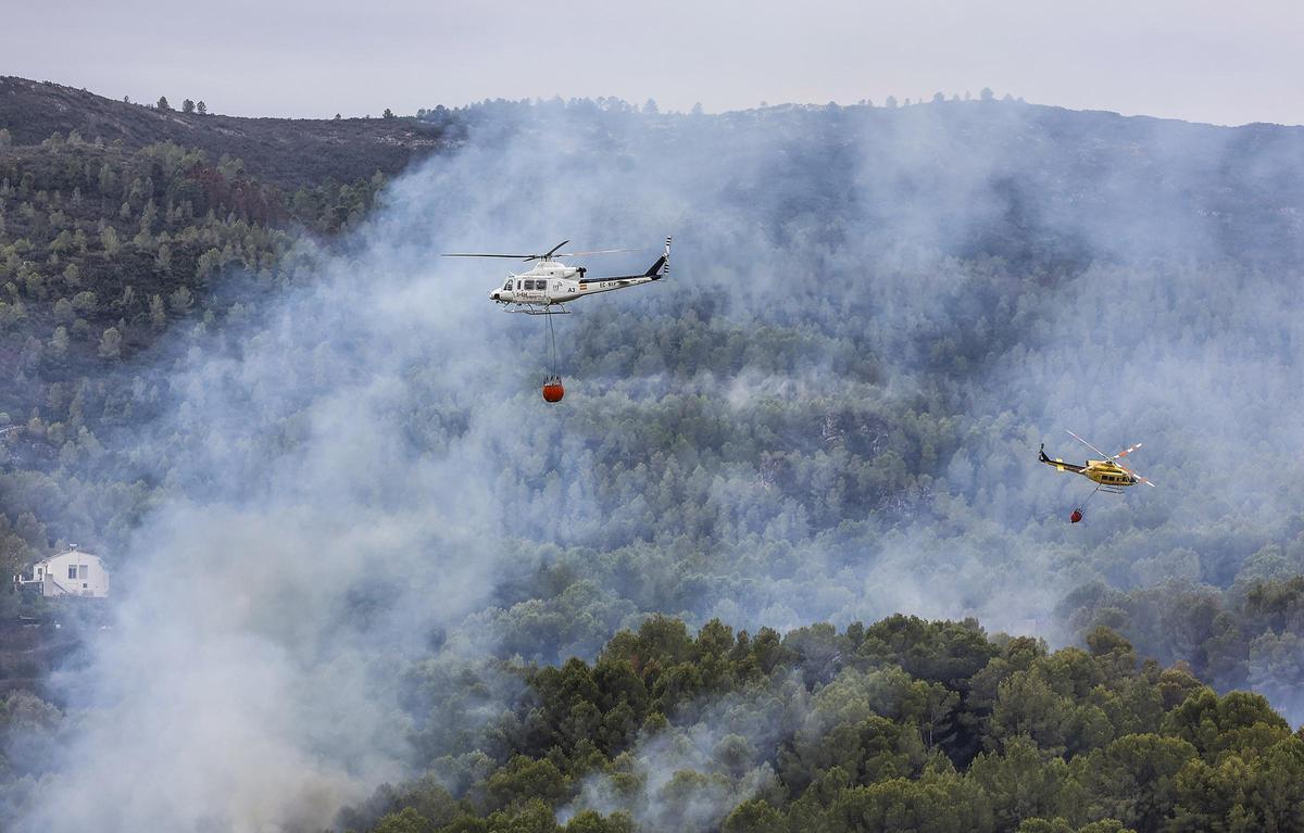 Archivo - Helicópteros de los bomberos trabajan en labores de extinción de un incendio forestal. ARCHIVO.