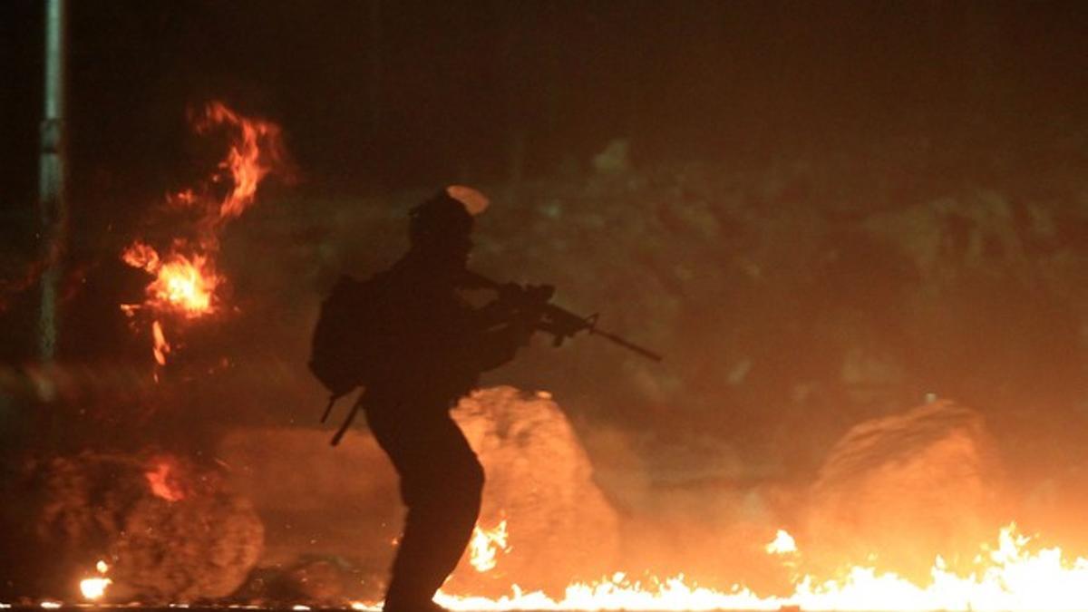 Un soldado israelí pasa entre neumáticos en llama, durante las protestas palestinas contra Israel, ayer en la franja de Gaza.