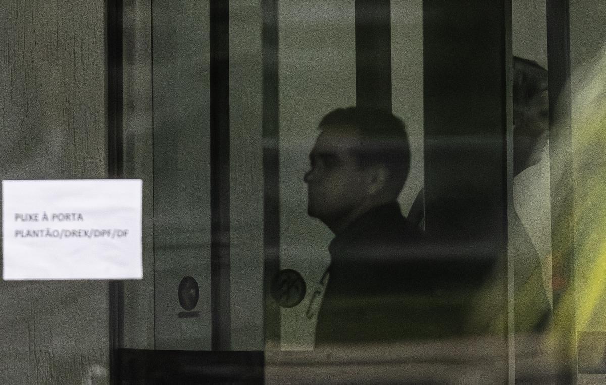 El expresidente de Brasil Jair Bolsonaro, detrás de una puerta de vidrio, en la Superintendencia de la Policía Federal en Brasilia (Brasil).