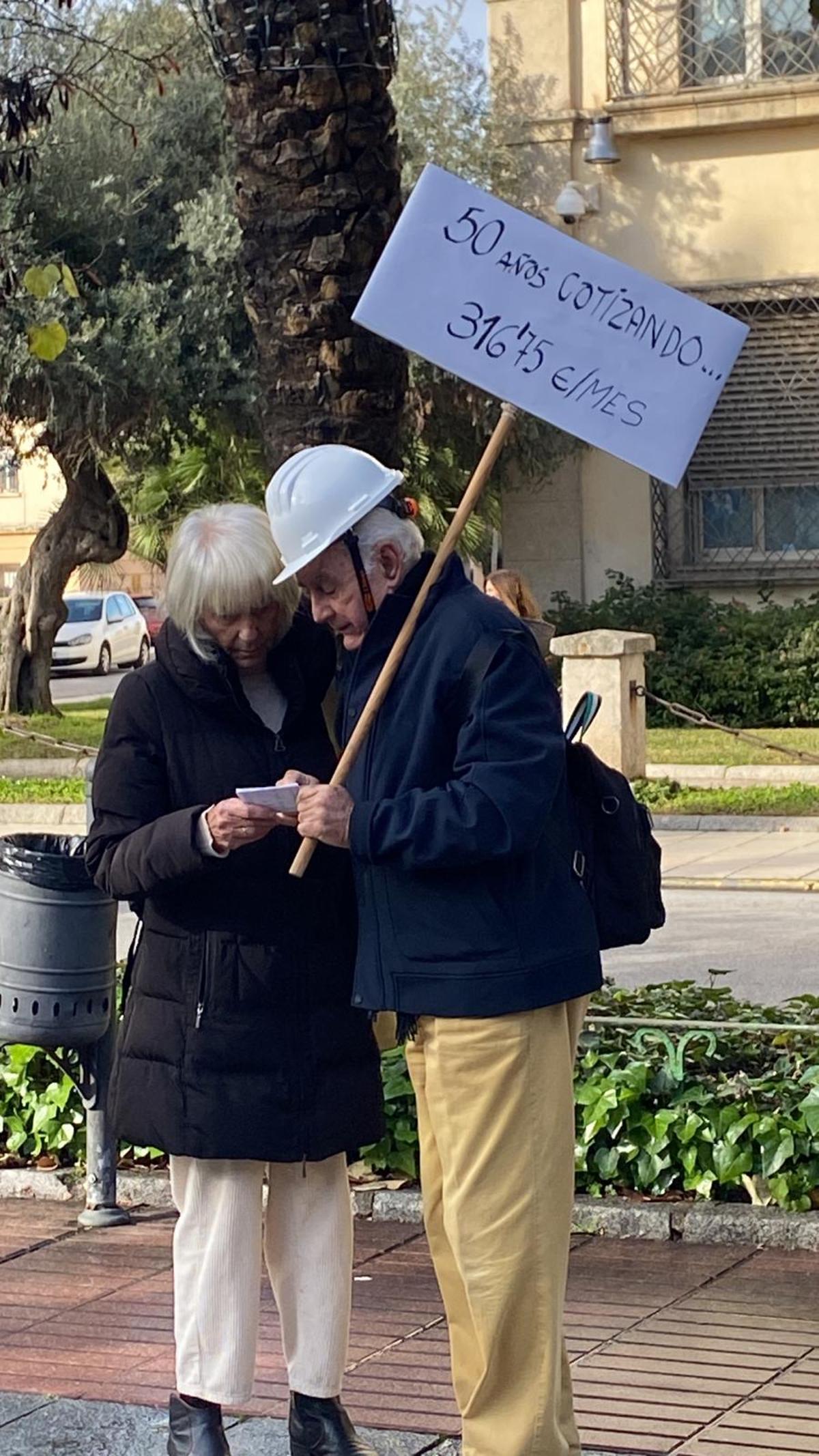 Dos de los manifestantes sostienen una pancarta con la pensión que recibirán tras décadas de cotización.