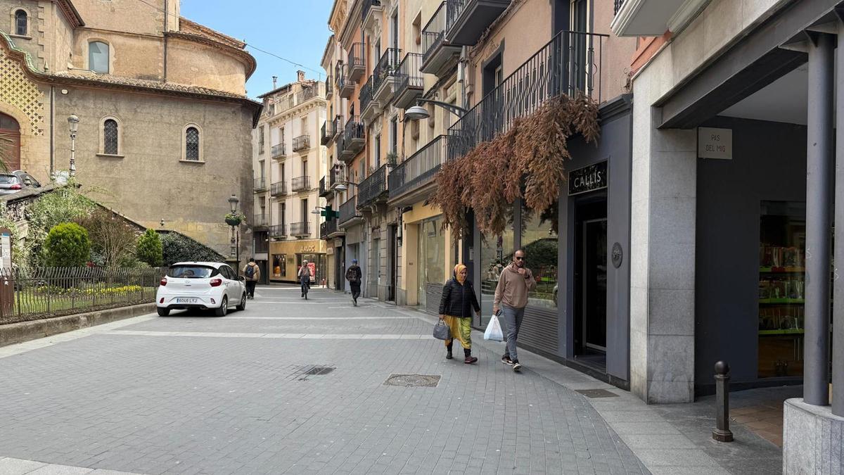 Un carrer del nucli antic d'Olot amb dos passejants