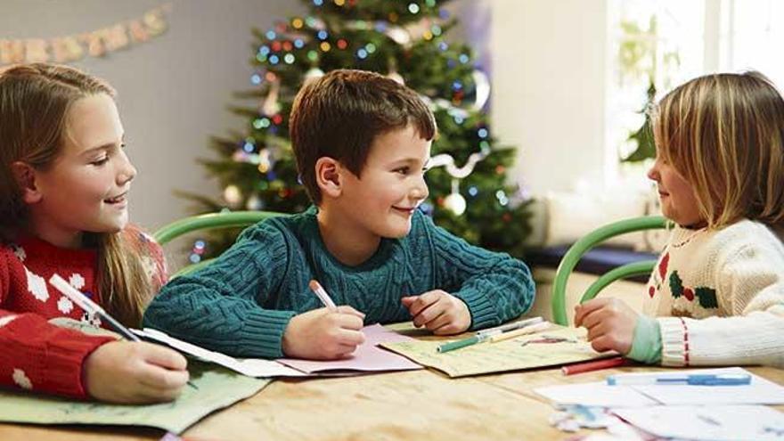 Unos niños escribiendo su carta a Papá Noel y a los Reyes Magos.