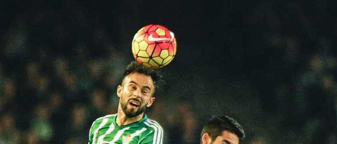 Molinero cabecea el balón ante Isco y un jugador del Betis.