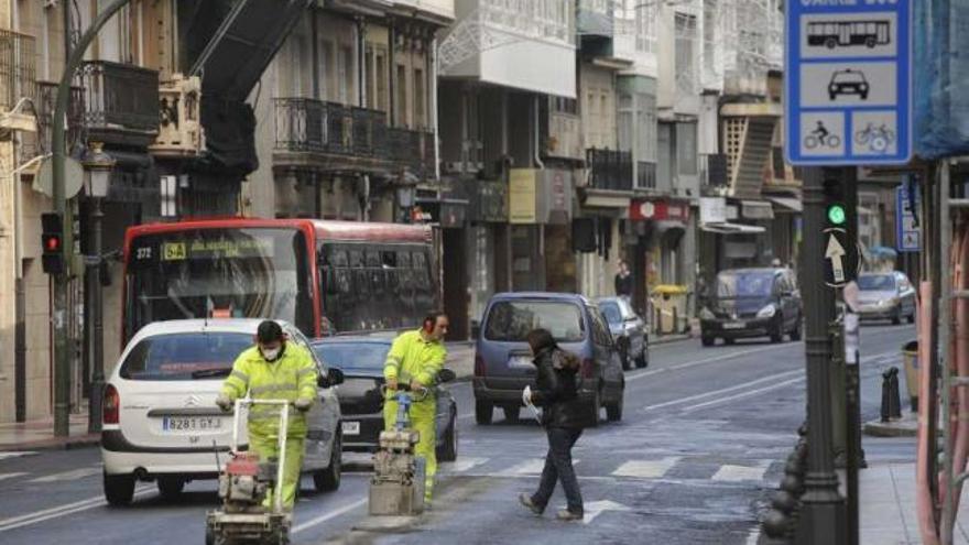 Operarios retiran, en diciembre, las marcas viales del carril bus en San Andrés. / carlos pardellas