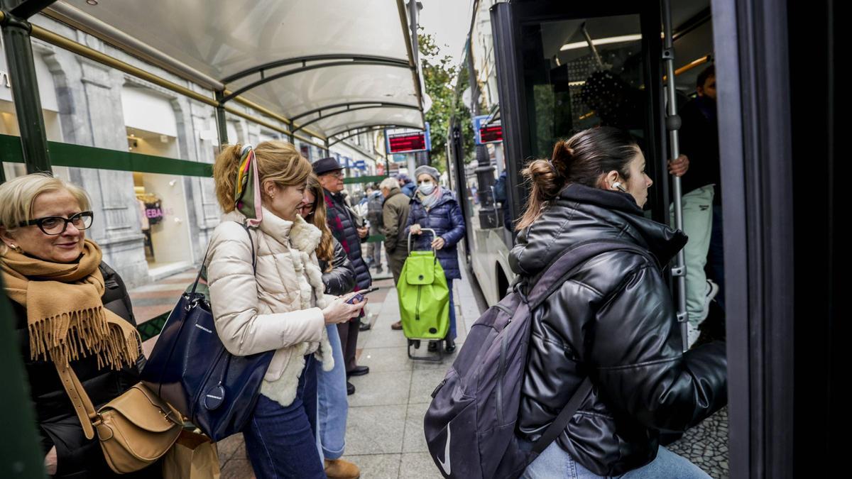 Usuarios esperan para subir a uno de los autobuses en la calle Uría.