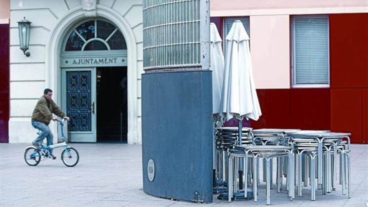 Mesas y pasarasoles de una terraza de bar de la plaza de la Vila junto al Ayuntamiento de Santa Coloma.