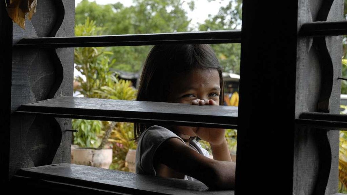 Una niña mirando a través de una ventana en Filipinas.