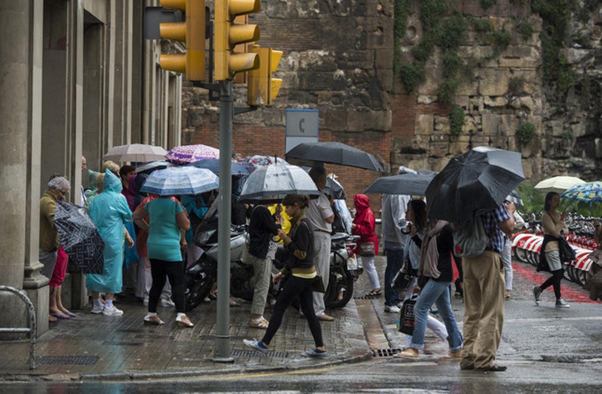 Uns vianants es protegeixen de la pluja a Barcelona, en una imatge d’arxiu.